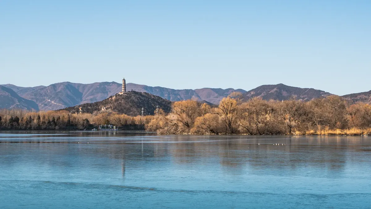 A tranquil landscape of the Summer Palace in Beijing showcasing the pagoda against the mountains.