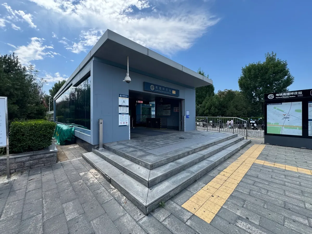 Exterior view of a Beijing metro station entrance under a clear blue sky.