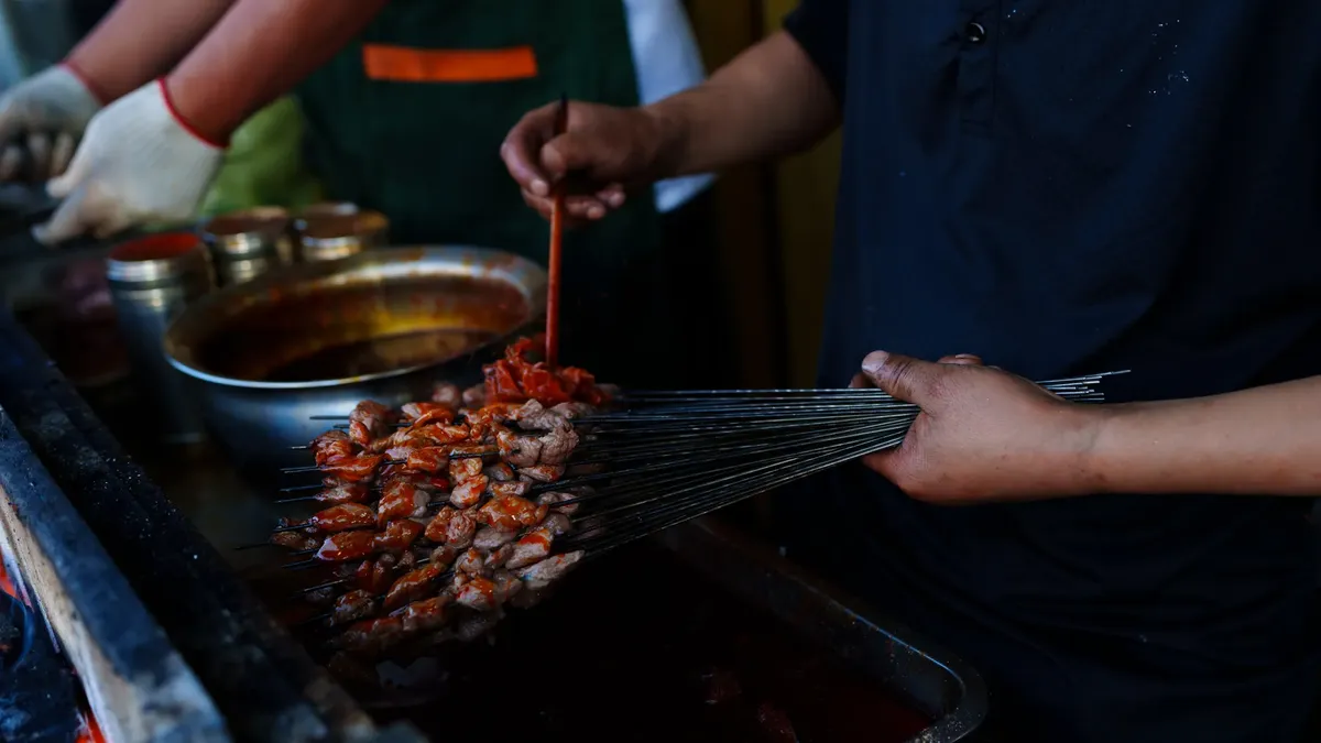A street vendor preparing traditional grilled skewers in Haibei, Qinghai, capturing vibrant cultural cuisine.